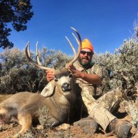 hunter sitting with mule deer